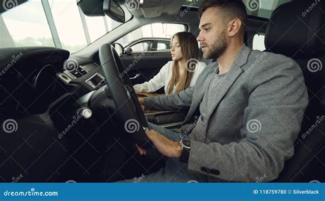 Handsome Guy And His Pretty Girlfriend Are Checking Interior Of Luxurious Automobile In Car