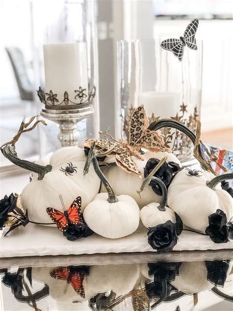 White Pumpkins And Black Roses Are Arranged On A Table With Candles In