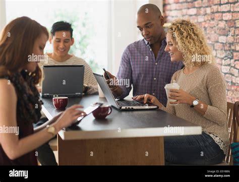 Friends Sitting In Cafe Using Laptops And Digital Tablets Stock Photo