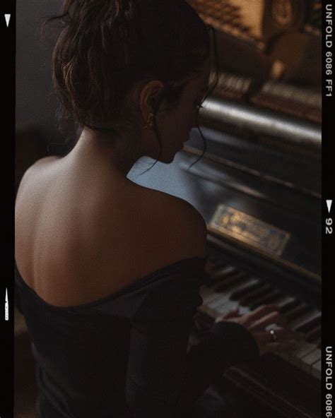 a woman sitting at a piano playing the keys and looking down into the room with her hands on the