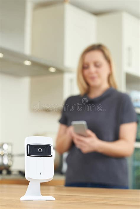 Woman Controlling Smart Security Camera Using App On Mobile Phone Stock
