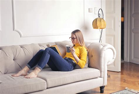 Woman Sitting On White Couch While Reading A Book · Free Stock Photo