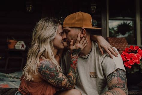 A Man And Woman Sitting Next To Each Other With Tattoos On Their Arms