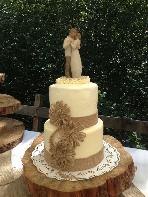 rustic elegance wedding cake with burlap lace and twine flowers sitting on a wood cookie the