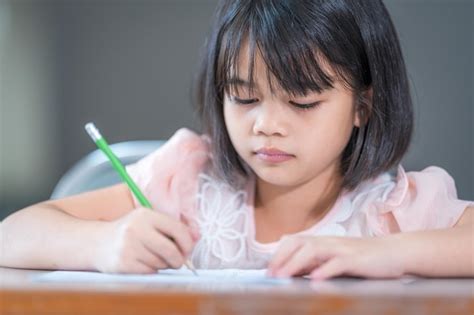 Premium Photo A Female Asian Kid Student Concentrate Writing On The