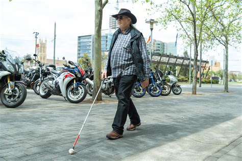 Image Of A Man Walking Down The Street With His White Cane Visability