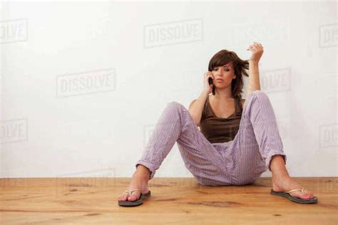Teenage Girl Sitting On Floor Leaning Against Wall Using Smartphone