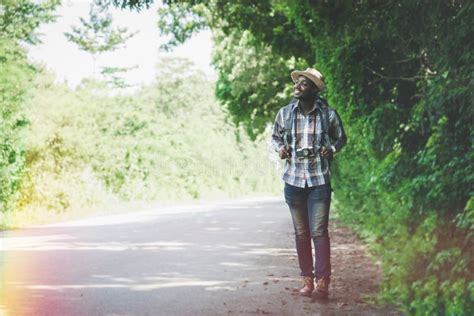 African Traveler Man Walking Alone On Rural Road With Full Of Trees On