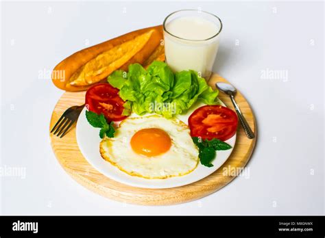 Breakfast With Bread Fried Eggs Milk And Vegetables And Fried Tomato Pieces Isolated On White
