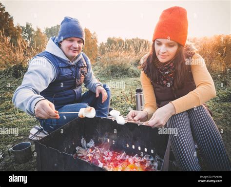 Happy Smiling Couple Roasting Marshmallows On Campfire On Nature