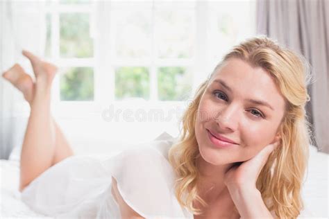 Pretty Blonde Lying On Her Bed Using Tablet Pc Smiling At Camera Stock