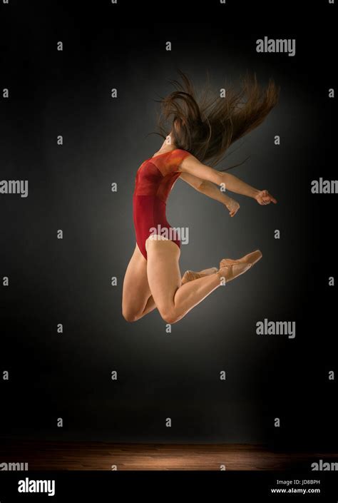 Female Ballet Dancer Jumping Mid Air With Hair Covering Face And Arms