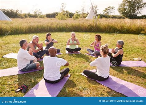 Group Of Mature Men And Women In Class At Outdoor Yoga Retreat Sitting