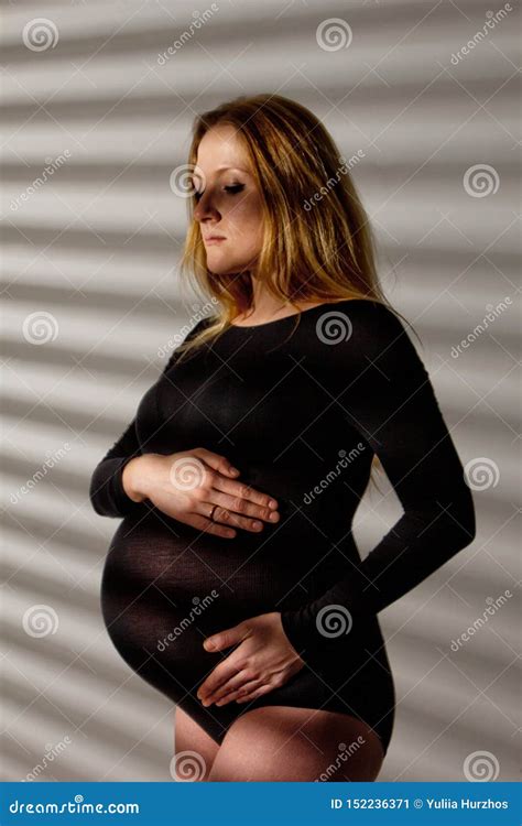 A Pregnant Woman In Lingerie With A Big Belly In The Ninth Month Of Pregnancy Is Hugging Her