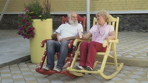 Old People Swings In Rocking Chair And Eats Popcorn Stock Video Footage
