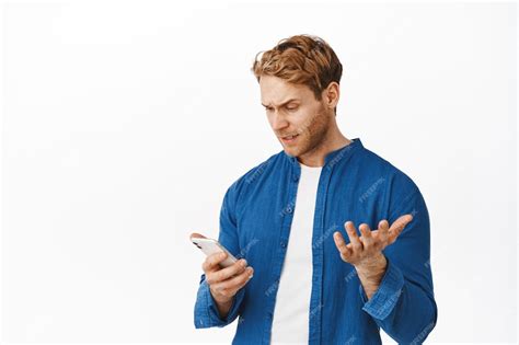 Free Photo Confused And Annoyed Young Man Looking At Smartphone