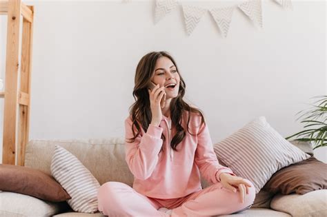 Free Photo Woman Dressed In Pink Pajamas Sitting On Her Couch Surrounded By Soft Pillows And