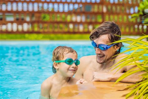 Dad And Son In Swimming Goggles Have Fun In The Pool Stock Photo