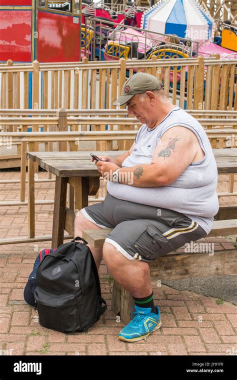 Mature Overweight Man Looking At His Mobile Phone In Dreamland