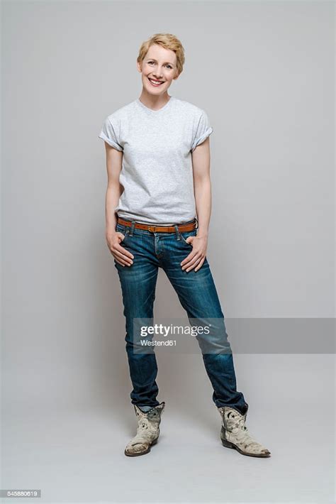 Relaxed Woman With Hands In Her Pockets Standing In Front Of Grey