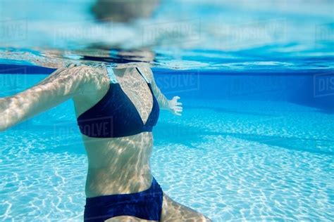 Underwater View Of Young Woman In Swimming Pool Neck Down Wearing