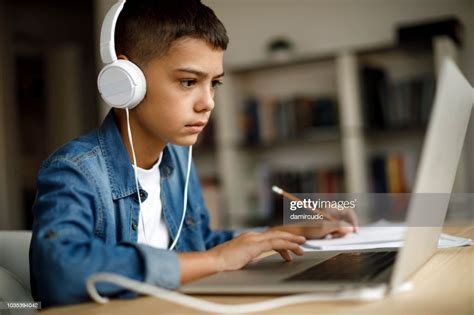 Teenage Boy Listening To Music While Doing Homework High Res Stock