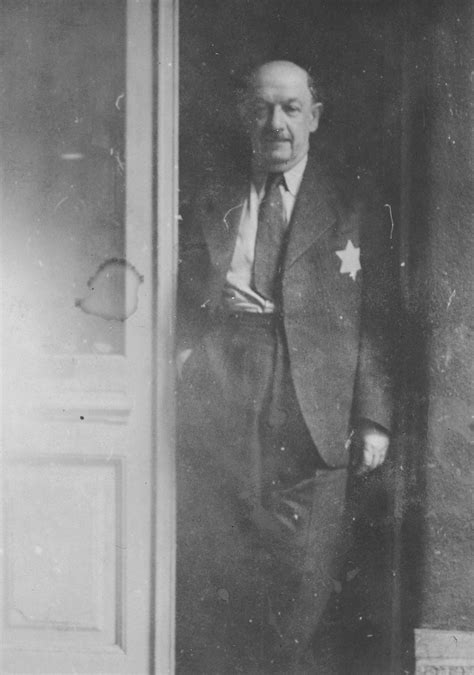 A Hungarian Jewish Man Stands In A Doorway Wearing A Yellow Star