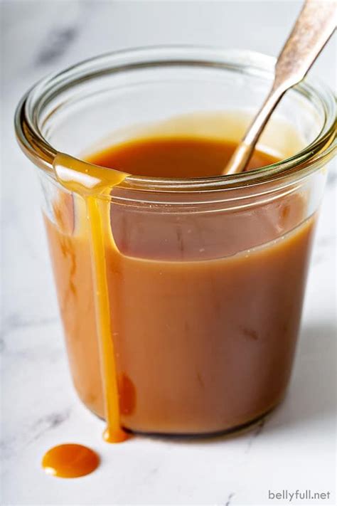 A Glass Jar Filled With Caramel Sauce On Top Of A White Counter Next To