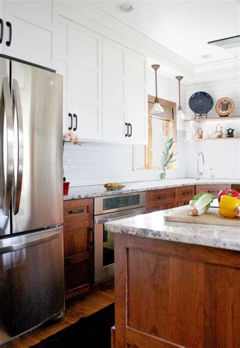 In this stylish kitchen, the main color of the cabinet is black which is accompanied with the light brown and white marble wall. Two Toned Kitchen Cabinet Trend