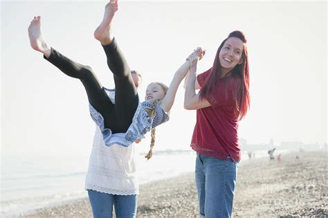 Playful Lesbian Couple Swinging Daughter On Beach Photograph By Caia Imagescience Photo Library