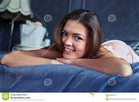 Positive Girl Looking At The Camera While Lying On The Bed Stock Image
