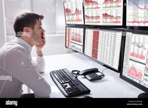 Side View Of A Sad Young Male Operator Looking At Graphs On Multiple