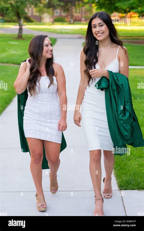 Two College Girls And Best Friends Walk On A Sidewalk While Holding