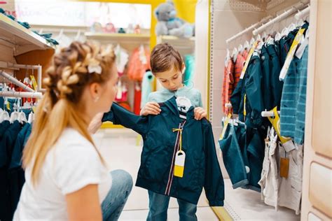 Premium Photo Mother With Her Little Boy Choosing Clothes In Kids Store