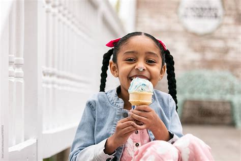 Young Girl Looks At Camera While Eating An Ice Cream Cone Del Colaborador De Stocksy Sean