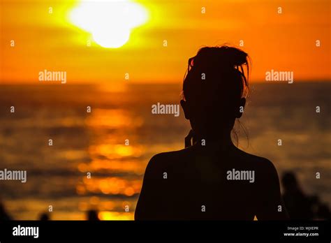 Rear View Of Silhouette Woman Standing At Beach During Sunset Stock