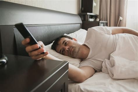 Premium Photo A Man Wakes Up In Bed And Looks At The Phone Turns Off
