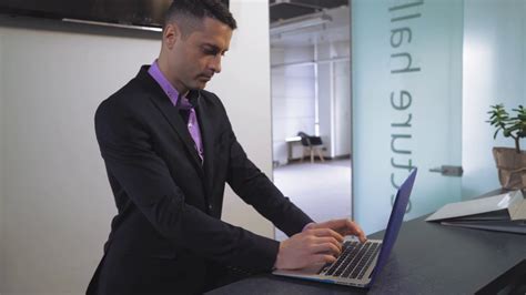 Portrait Handsome Employee Standing At Reception Desk Typing On Laptop