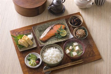 A Wooden Tray Topped With Different Types Of Food Next To Cups And