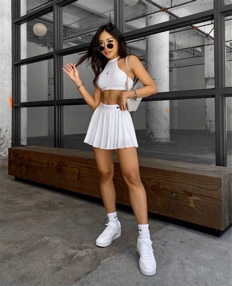A Woman Posing In A White Outfit And Tennis Shoes With Her Hands On Her Hips