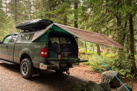 A Pick Up Truck Parked In The Woods With Its Roof Tent On It S Back