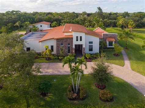 an aerial view of a home in the middle of a lush green area with palm trees