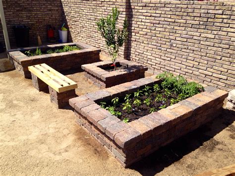 An Outdoor Garden Area With Brick Benches And Plants In The Center