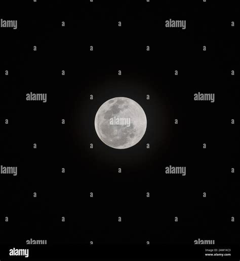 Bright White Full Moon In The Night Sky With Solar Rings In Background
