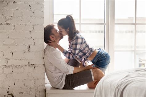 12 things men do that make women fall deeper in love. Sensual Young Woman Kissing Man Sitting On Windowsill ...