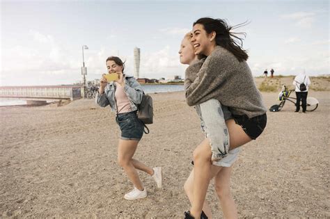 Female Friend Giving Piggyback Ride While Teenage Girl Photographing At