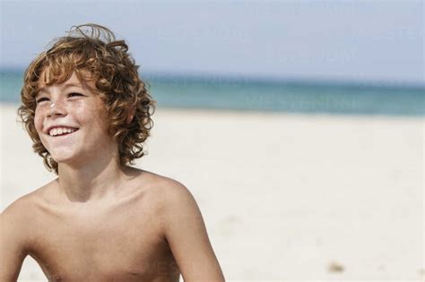 Spain Boy Sitting On Beach Smiling Stock Photo