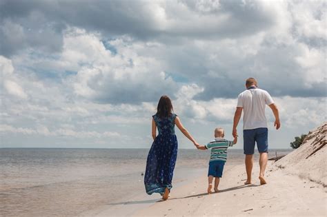 Mamá Papá E Hijo Caminando Por La Playa De Arena Tomados De La Mano