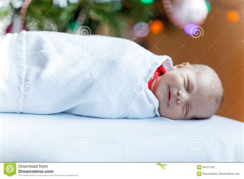 One Week Old Newborn Baby Wrapped In Blanket Near Christmas Tree Stock