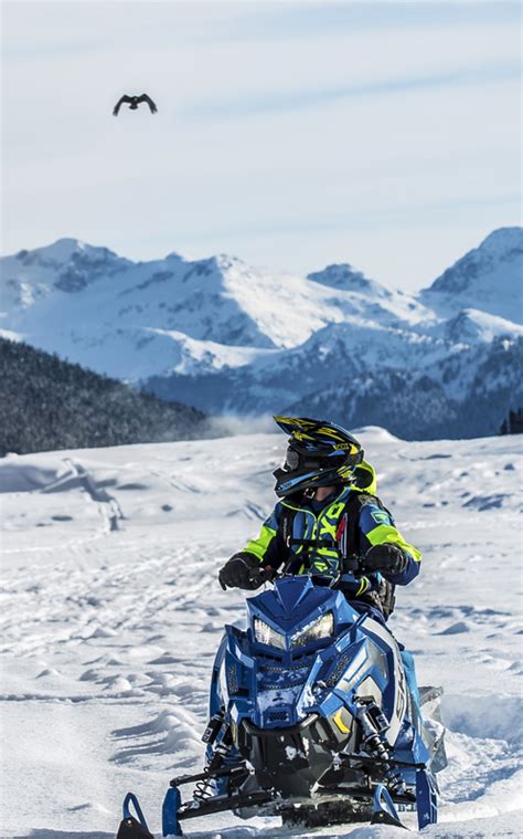 Person Riding Snowmobile With Mountains In The Background Image Free